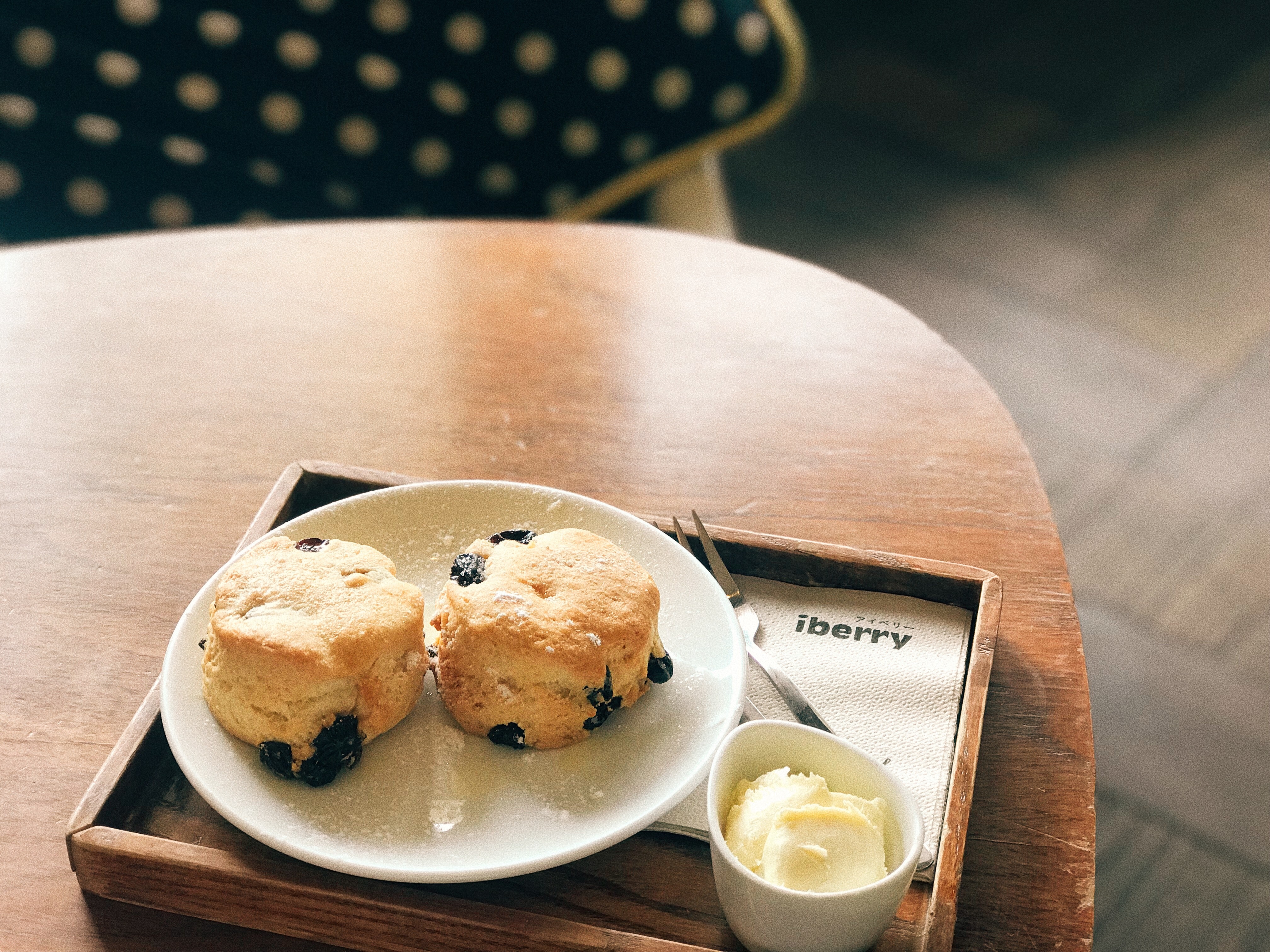 Scones with dried fruit on a white plate, with a side of clotted cream in a small bowl